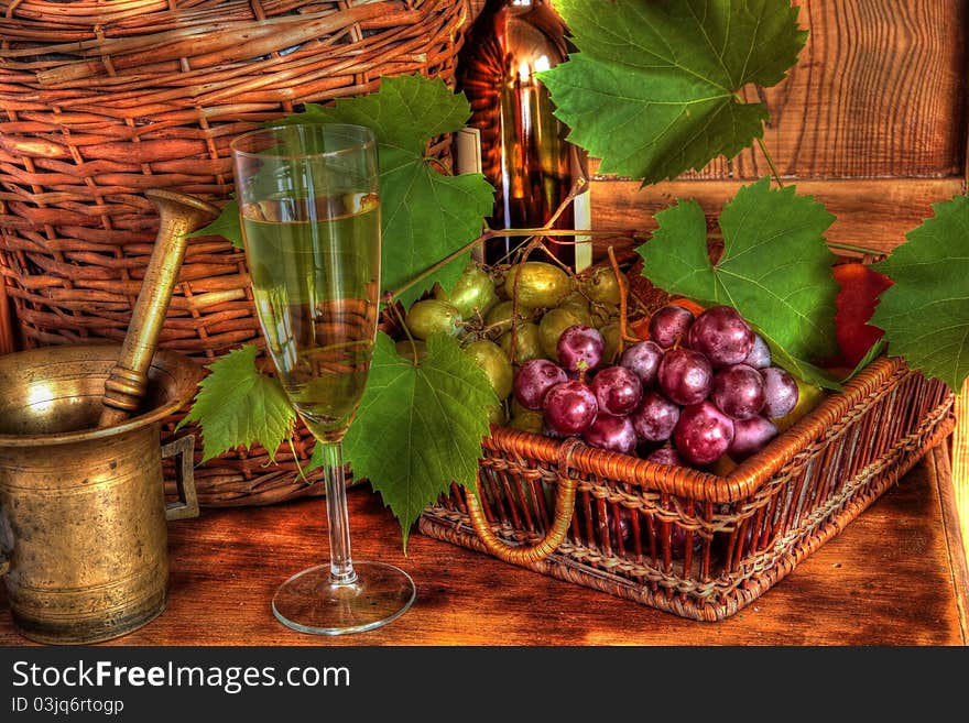 Glass of wine, wicker basket with grapes, grapevine,mortar on wooden background. Glass of wine, wicker basket with grapes, grapevine,mortar on wooden background.