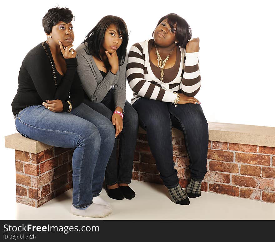 Three bored teen friends sitting togther on a short brick wall with ample white space for your text. Three bored teen friends sitting togther on a short brick wall with ample white space for your text.