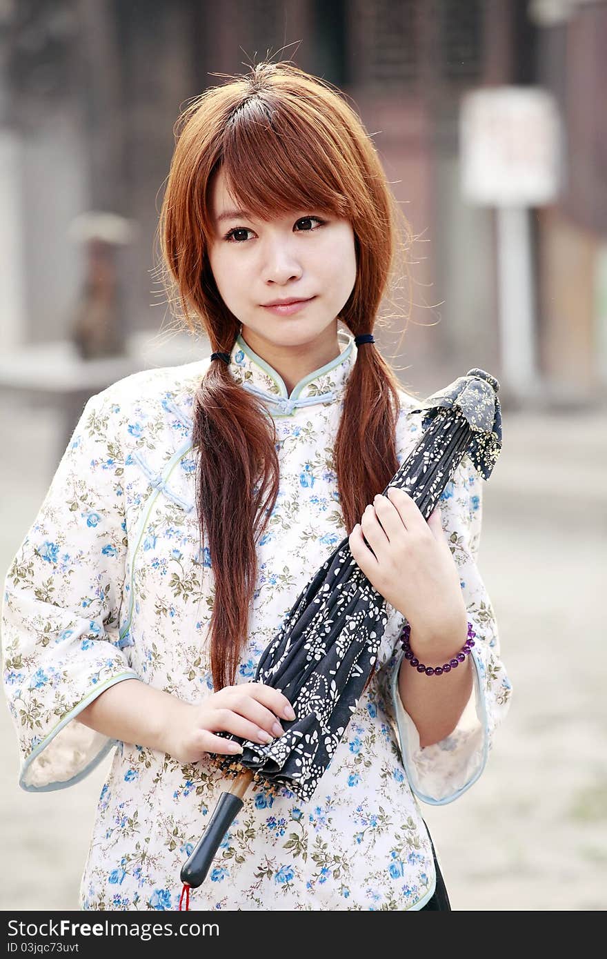 Traditional Chinese beauty holding the umbrella outdoor.