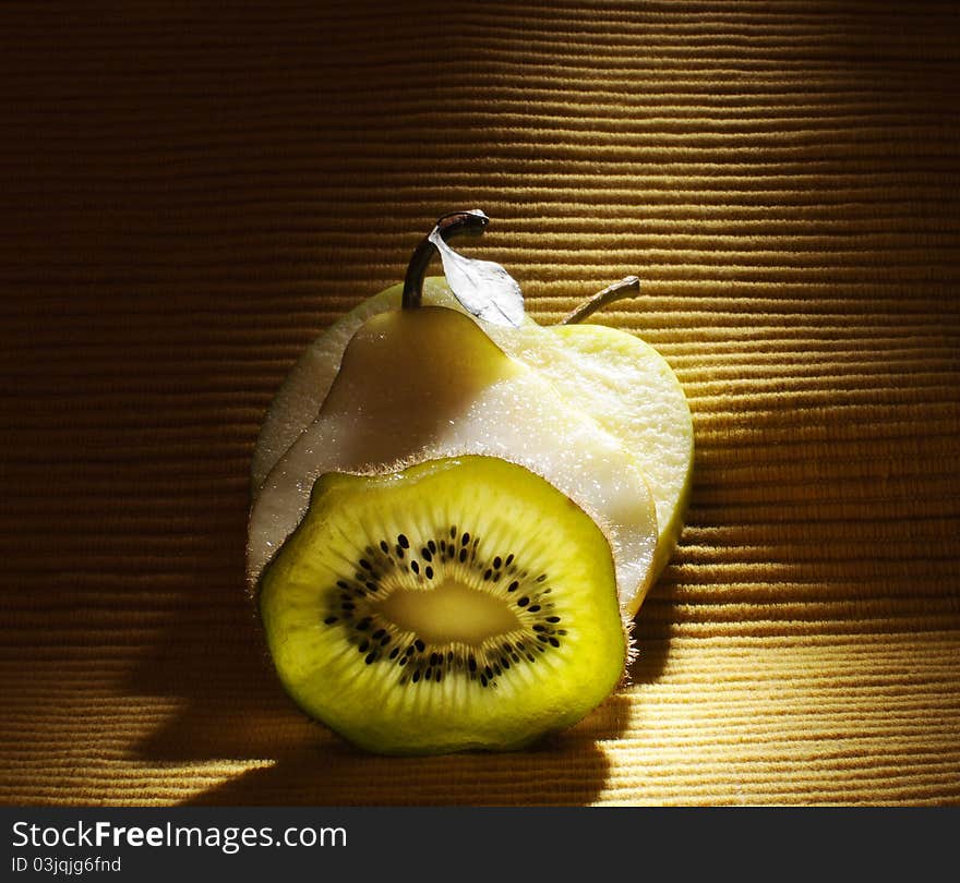 Fruits - kiwi, apple and pear on the table with yellow background