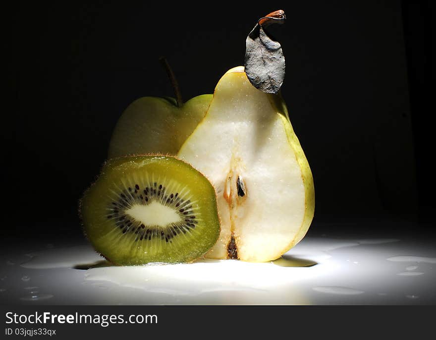 Fruits - kiwi, apple and pear on the table with dark background