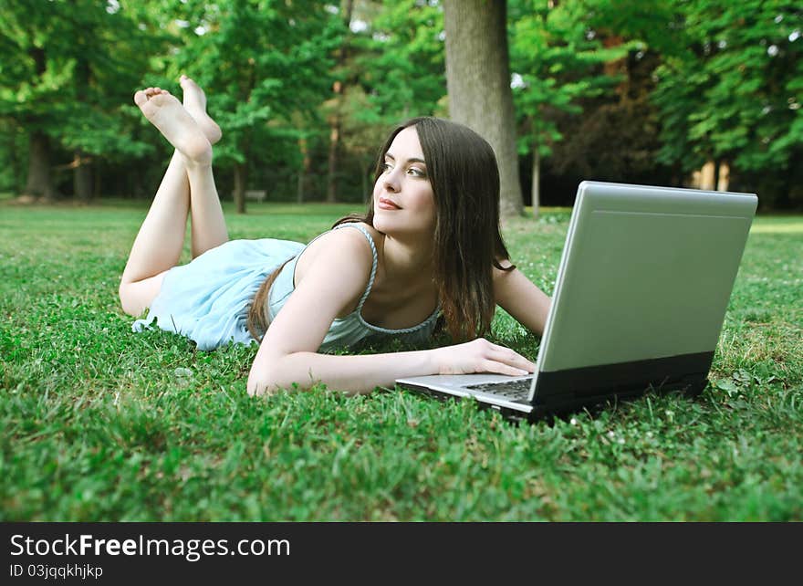 Beautiful woman lying on a green meadow and using a laptop. Beautiful woman lying on a green meadow and using a laptop