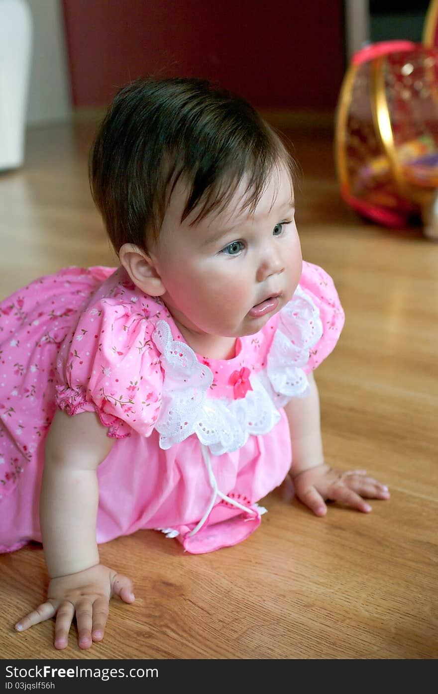 Beautiful little baby in pink dress at home. Shallow DOF