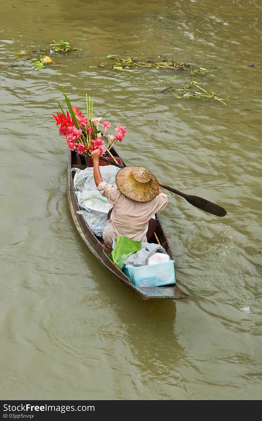 Lady selling flower from her boat at Damnoen Saduak Floating Market in Thailand.