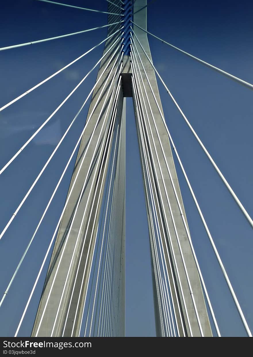 Suspension cables at modern highway bridge against clear blue sky at sunny summer day.