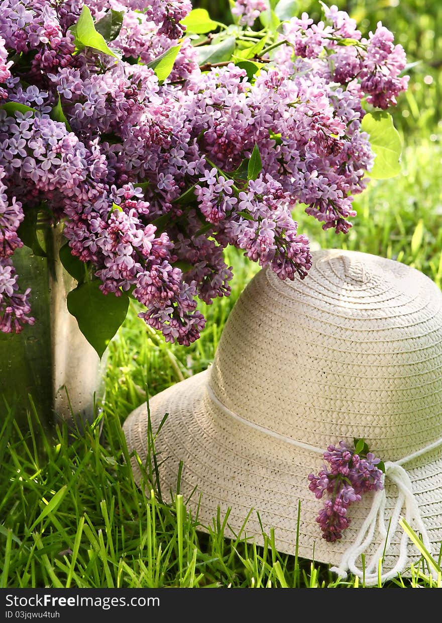 Bunch of lilac  and hat in garden