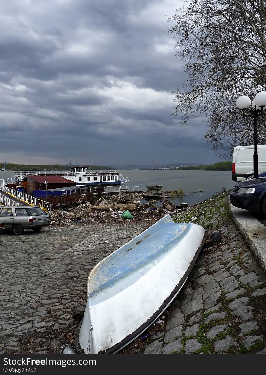 Scene at river bank with old boat and scrap against stormy sky. Scene at river bank with old boat and scrap against stormy sky.