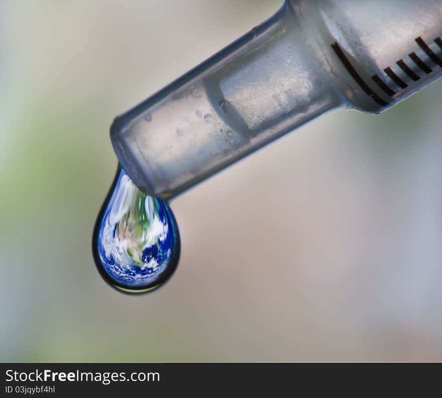 Earth dripping in water drop from eye dropper.