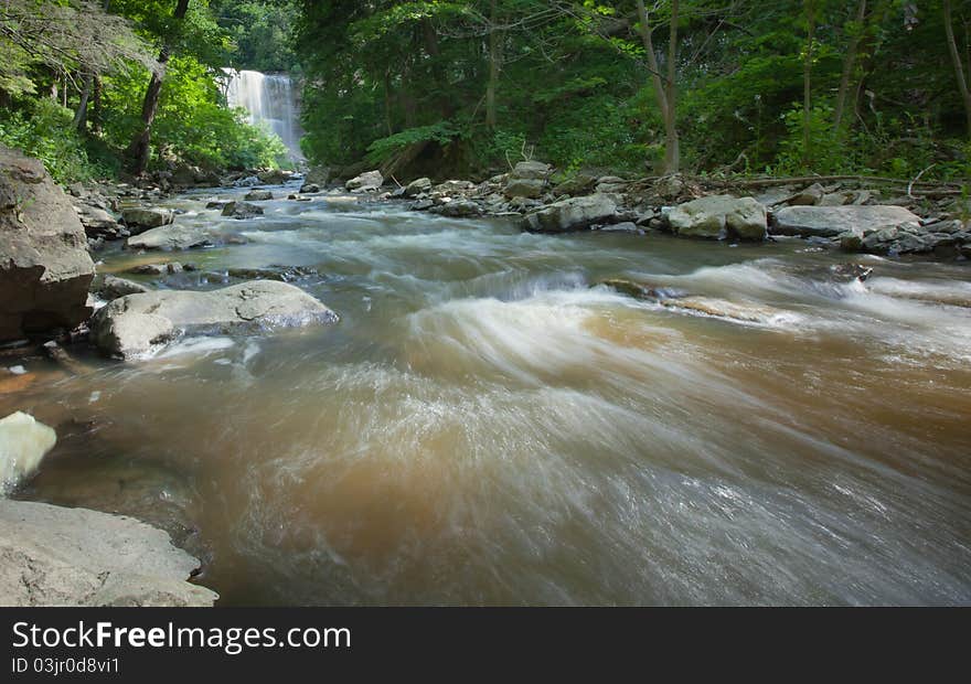 Fast moving river with waterfall in the background.