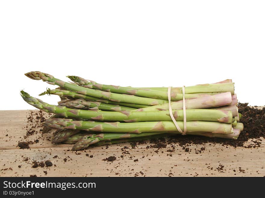 Bunch of freshly picked asparagus spears on a wooden board with residual soil