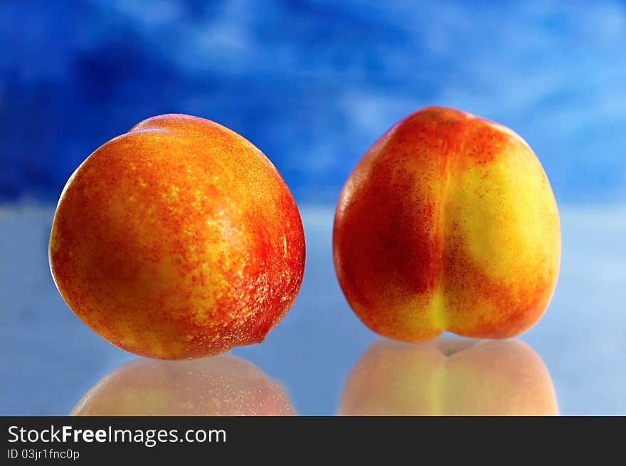 Two nectarine with blue background.