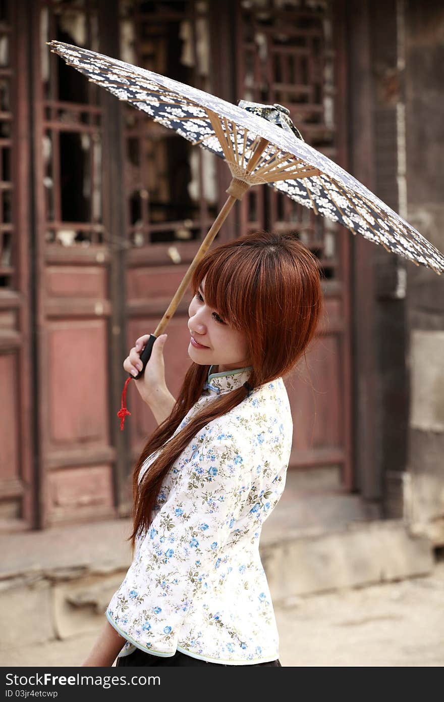 Happy Chinese girl holding the umbrella posing outdoor.