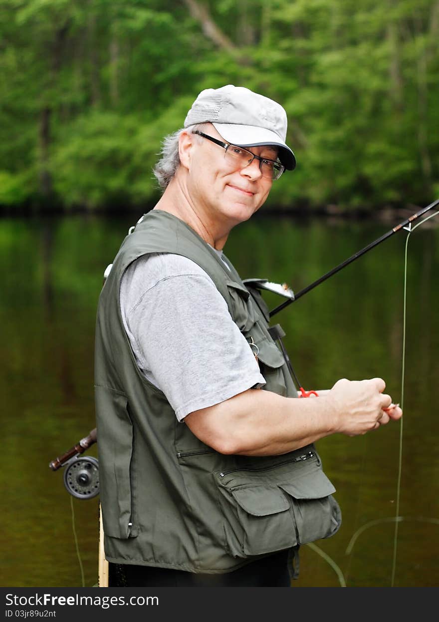 A fly fisherman smiles as he prepares to go fishing