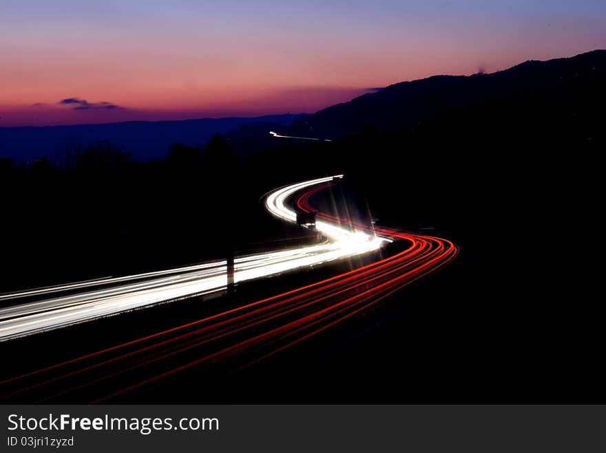 Highway with car trails in front of sunset