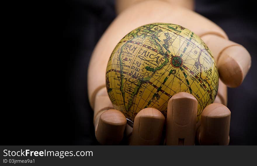 Global in wooden hand, on black background