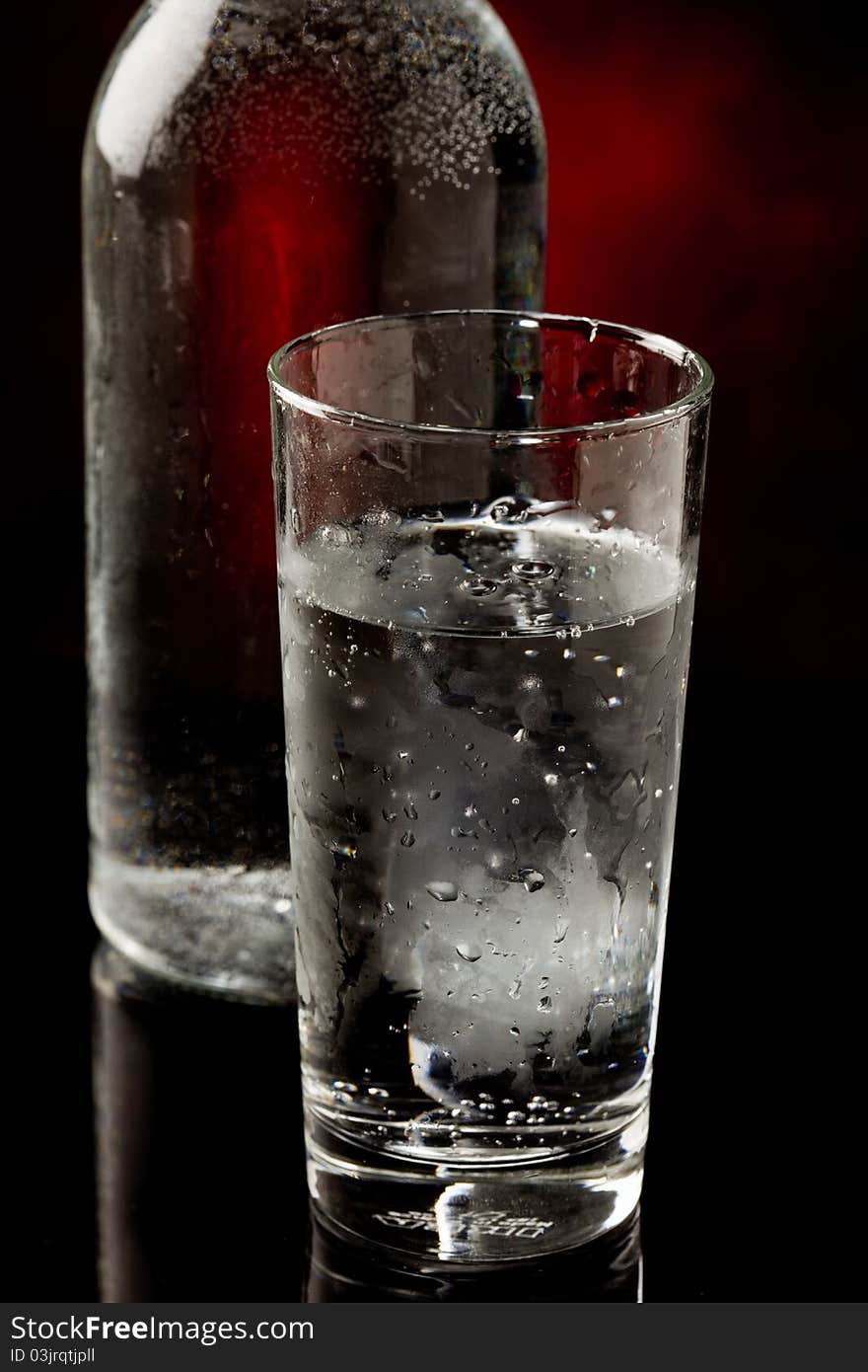 Photo of water glass and bottle standing on black glass table