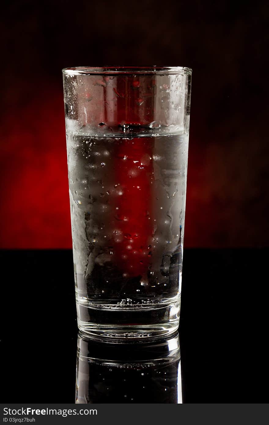 Photo of a water glass with sparkling cold water inside on black glass table