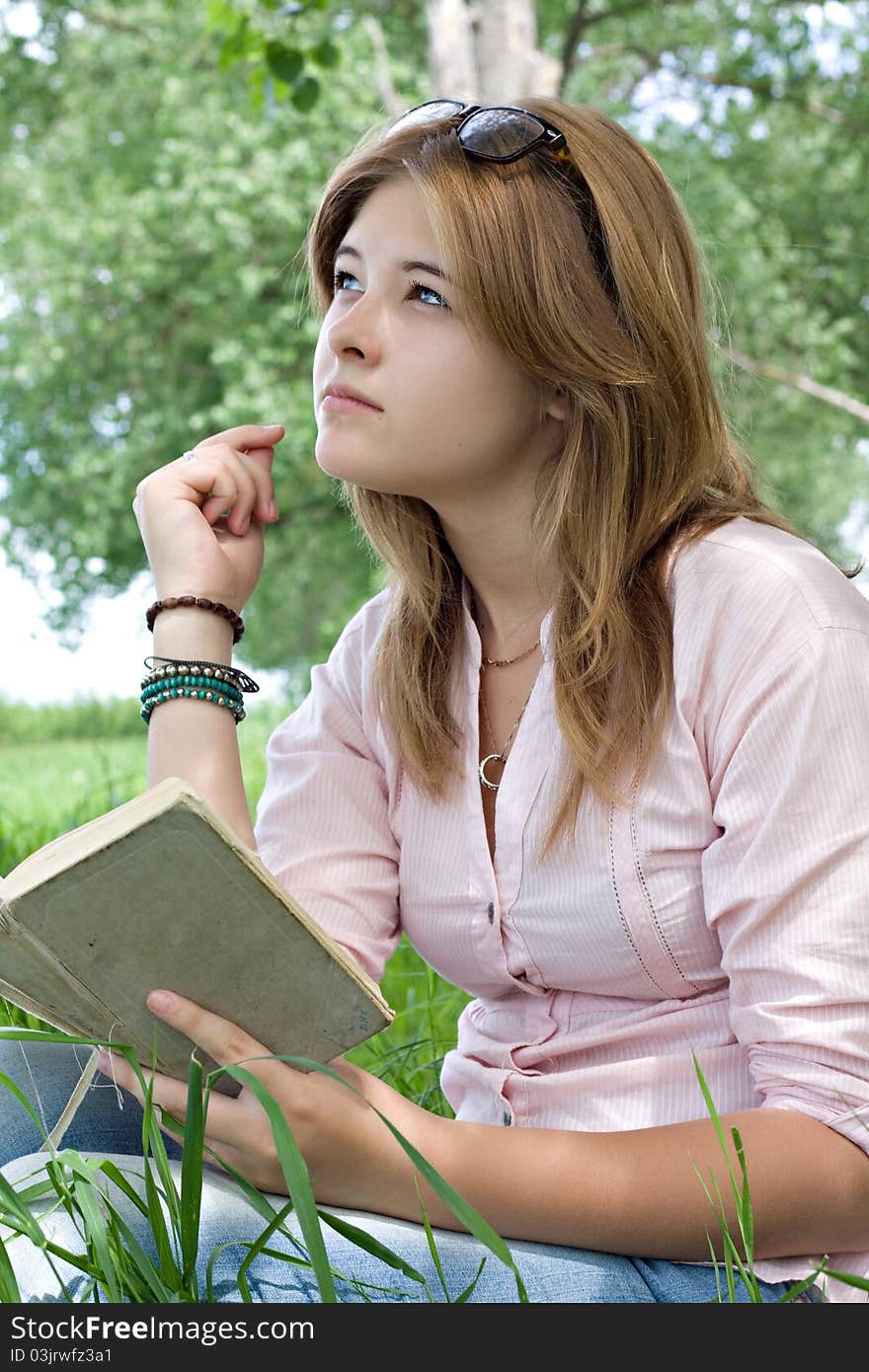 Teenager girl reading book in park