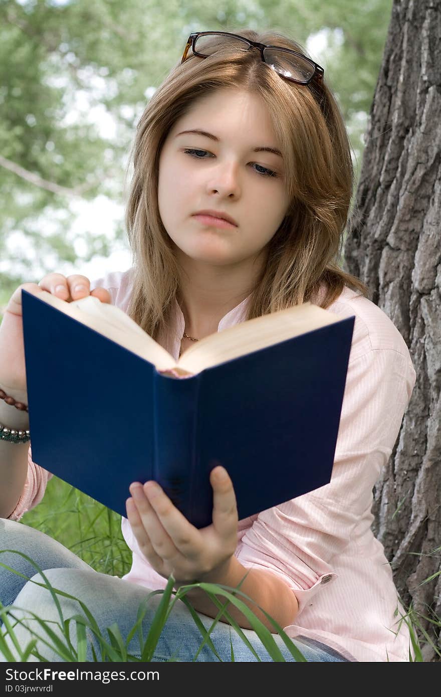 Teenager girl reading book in park