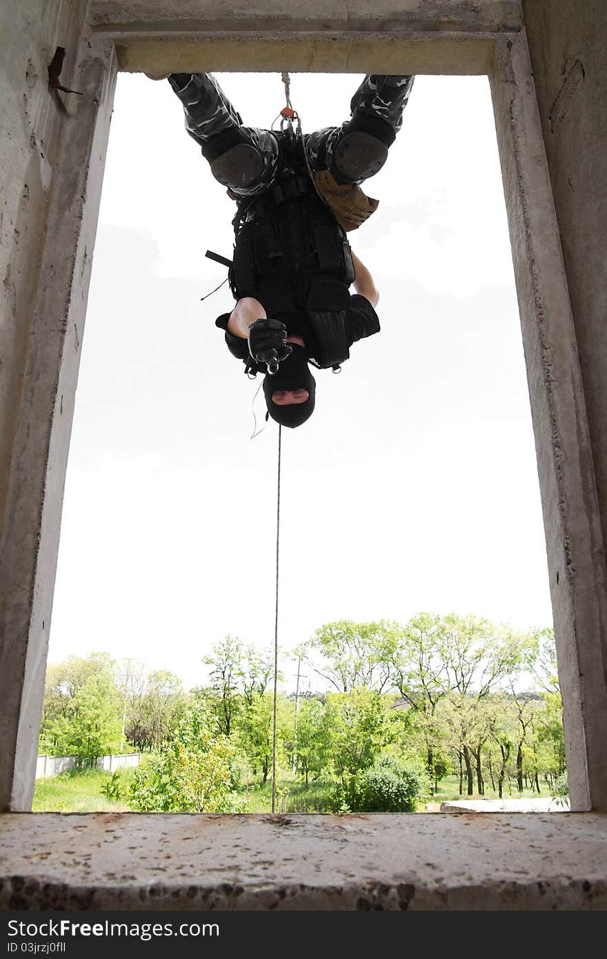 Soldier in black mask hanging on rope with pistol