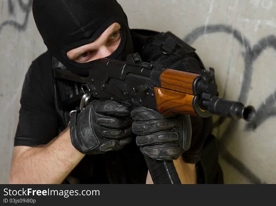 Soldier in black mask targeting with AK-47 rifle