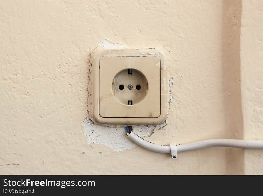 This is a photo of an old and dangerous socket, covered with many layers of paint, and connected externally with a cable. This is a photo of an old and dangerous socket, covered with many layers of paint, and connected externally with a cable.