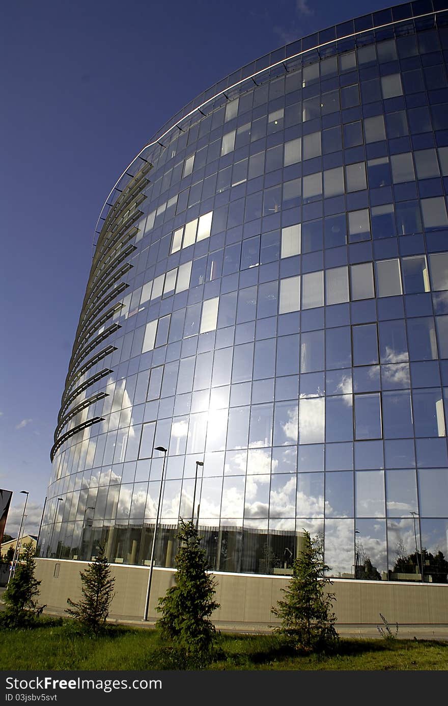 Modern oval office building made of glass with clouds reflection on the surface. Modern oval office building made of glass with clouds reflection on the surface