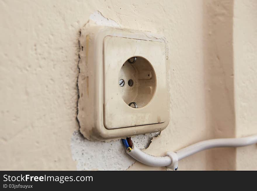 This is a photo of an old and dangerous socket, covered with many layers of paint, and connected externally with a cable. This is a photo of an old and dangerous socket, covered with many layers of paint, and connected externally with a cable.