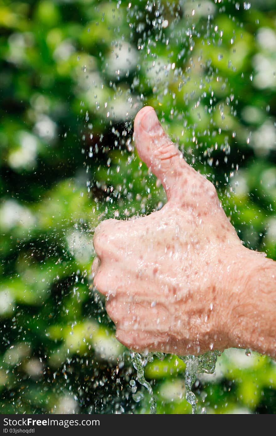 Thumbs up under falling water