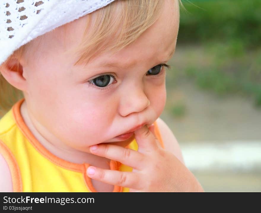 Portrait of the little girl with fingers in a mouth