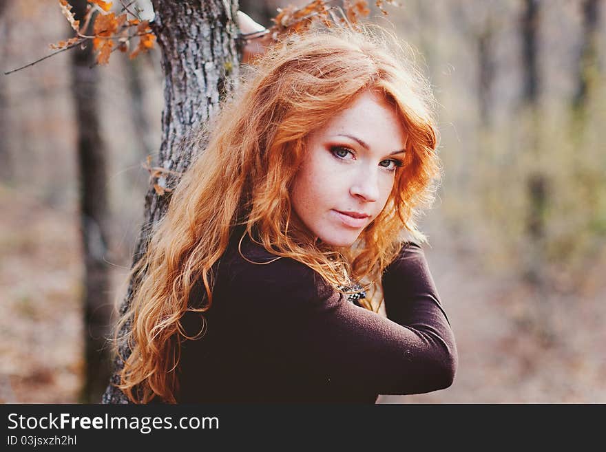 The red-haired girl in autumn leaves outdoor shot