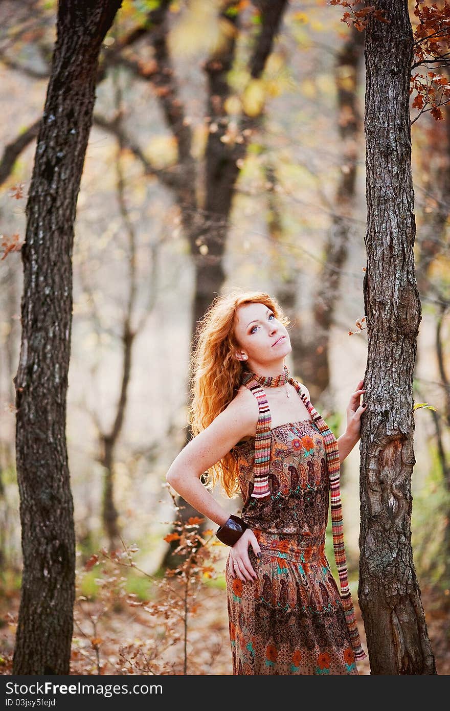 The red-haired girl in autumn leaves outdoor shot