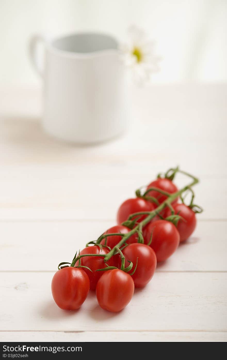 Cherry tomatoes on a white table, white flower in background