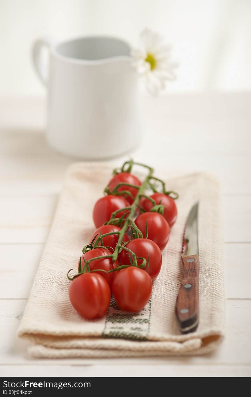 Cherry tomatoes on a white table, white flower in background