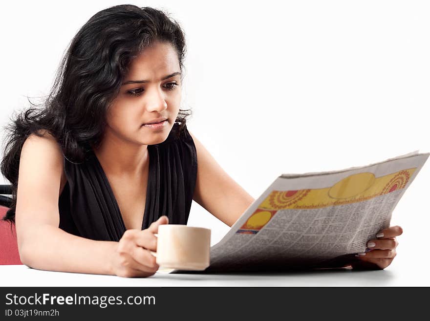 Pretty indian woman reading the newspaper and smiling with coffee. Pretty indian woman reading the newspaper and smiling with coffee