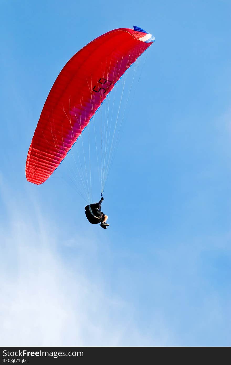 Red Paraglider Flying In Blue Sky