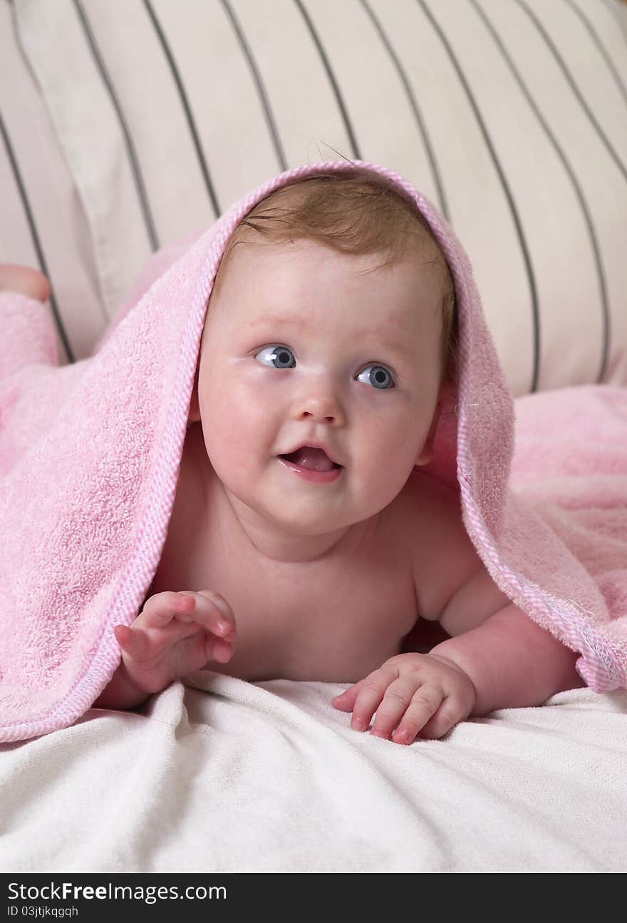 Little baby girl under soft pink towel