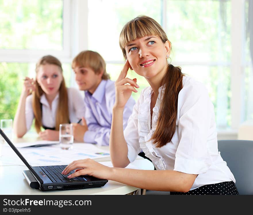 Young business woman working in office with collegues on background. Young business woman working in office with collegues on background