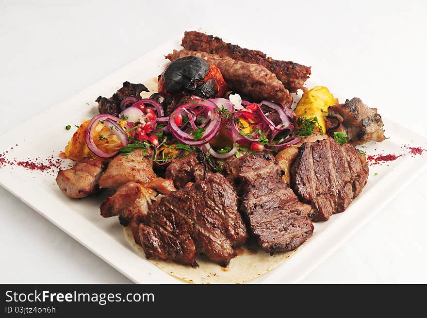 Meat allsorts with vegetables on a white plate