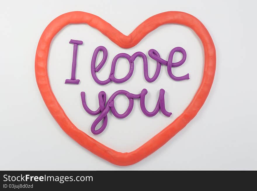 A plasticine lettering I love you inside a plasticine red heart.