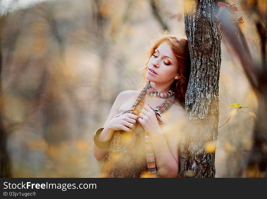 The red-haired girl in autumn leaves outdoor shot