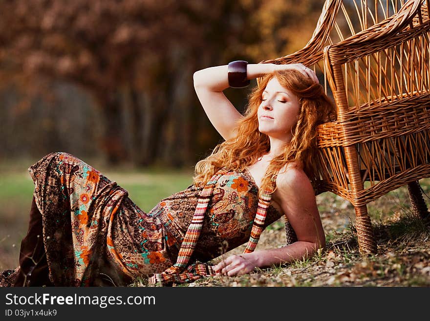 The red-haired girl in autumn leaves outdoor shot