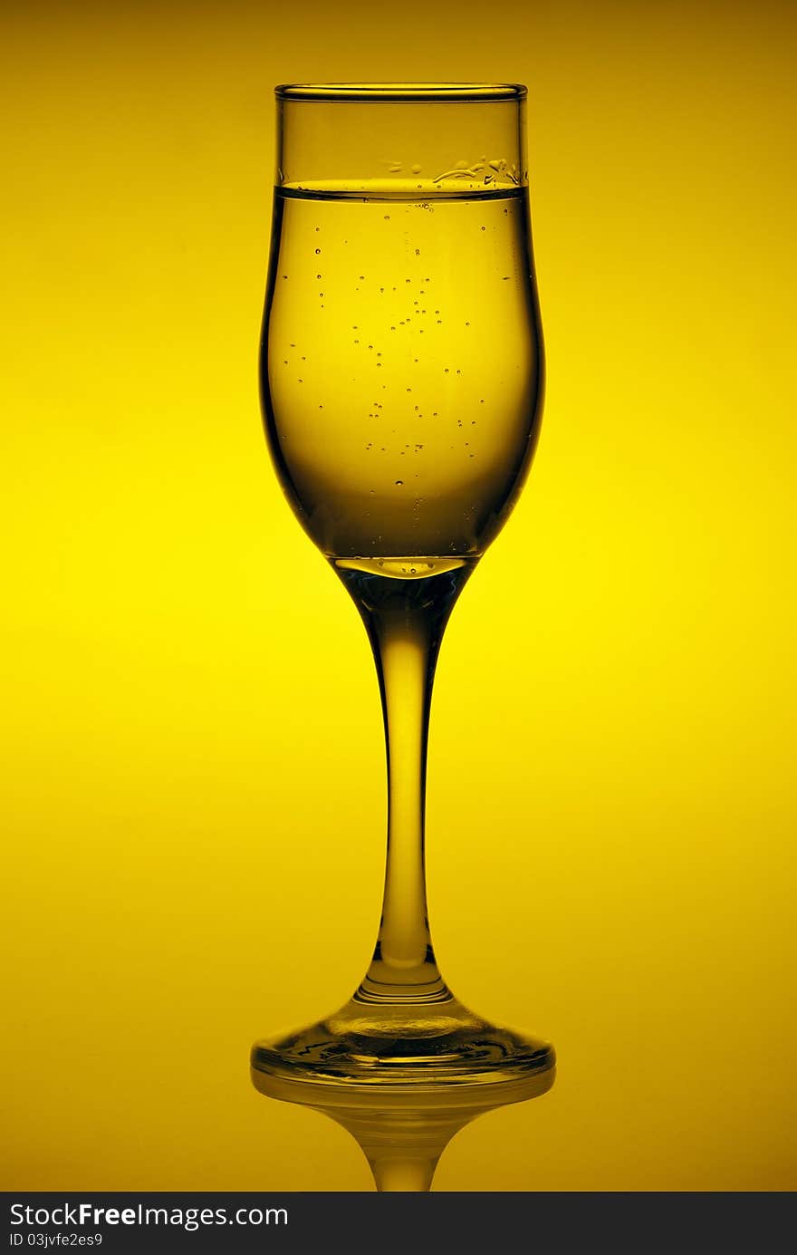 Glass with mineral water isolated on a yellow background