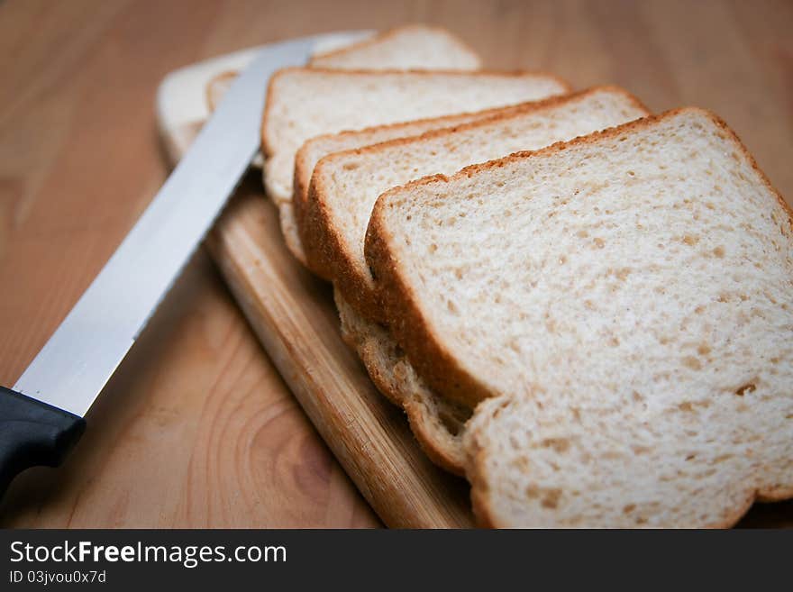 Sliced bread with knife, on cutting board.