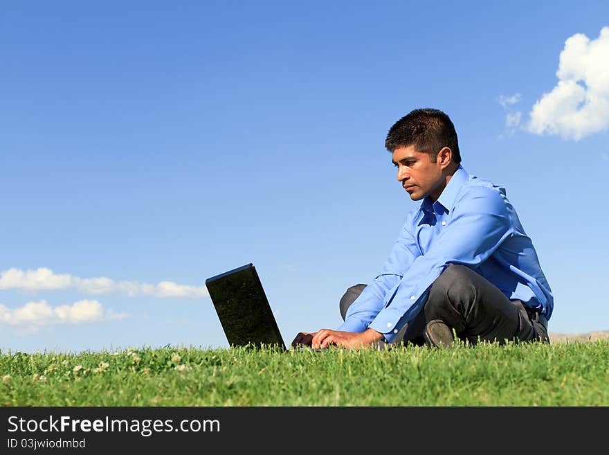 Young businessman working on his laptop at the park. Young businessman working on his laptop at the park