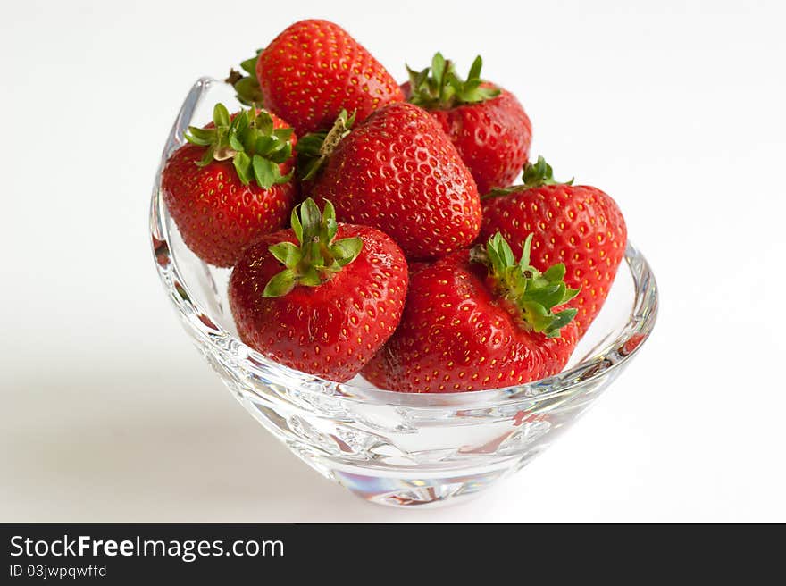 A crystal glass bowl of ripe red strawberries. A crystal glass bowl of ripe red strawberries