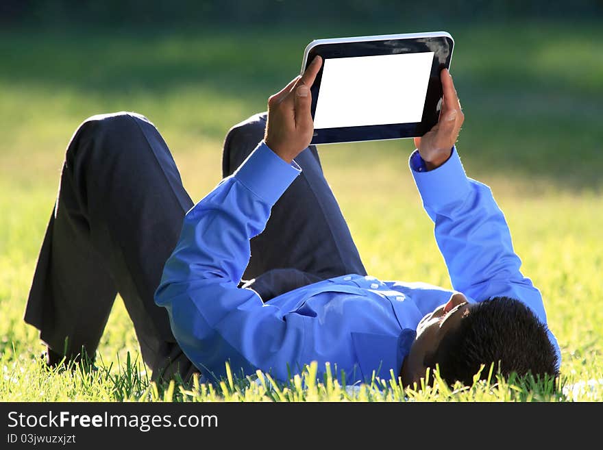 Young businessman relaxing on green grass with digital tablet in hands. Young businessman relaxing on green grass with digital tablet in hands