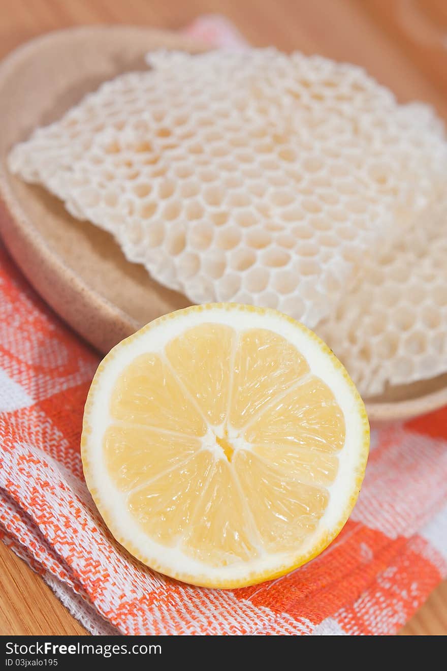 Honeycomb and half of lemon on orange tablecloth. Honeycomb and half of lemon on orange tablecloth