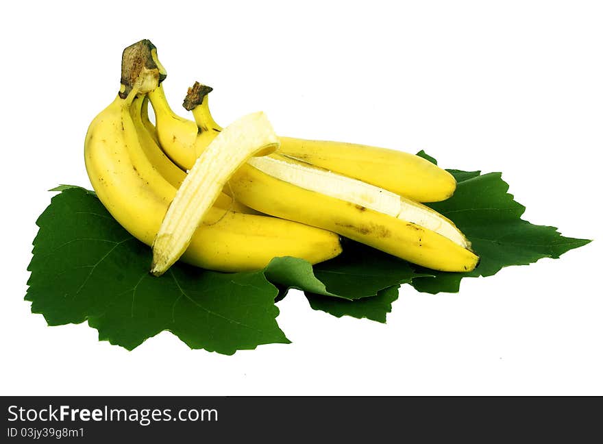 Cluster of ripe bananas lay on green leaves.