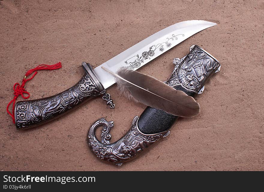 The hunting knife with a sheath on a sandy grount. The hunting knife with a sheath on a sandy grount.